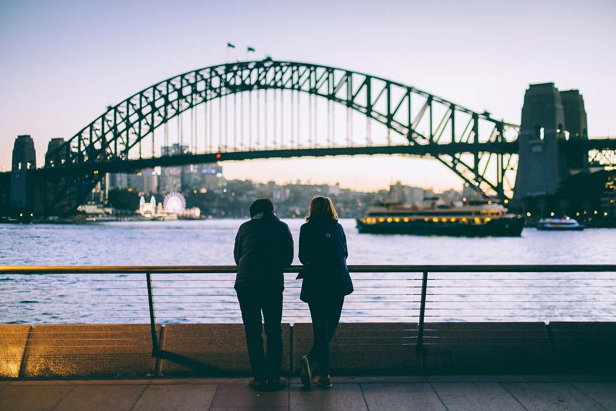 human man and woman standing beside each other in front of body of water people