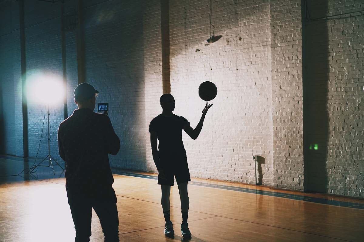 human man capturing silhouette photo of man spinning basketball people