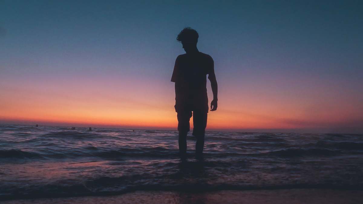 human man standing at beach during sunset standing