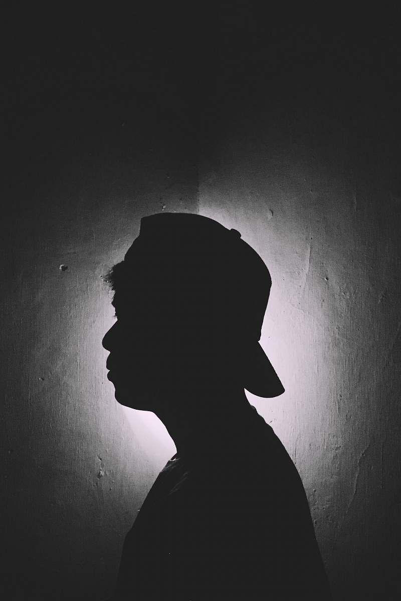 silhouette man wearing cap inside dark roomn grey