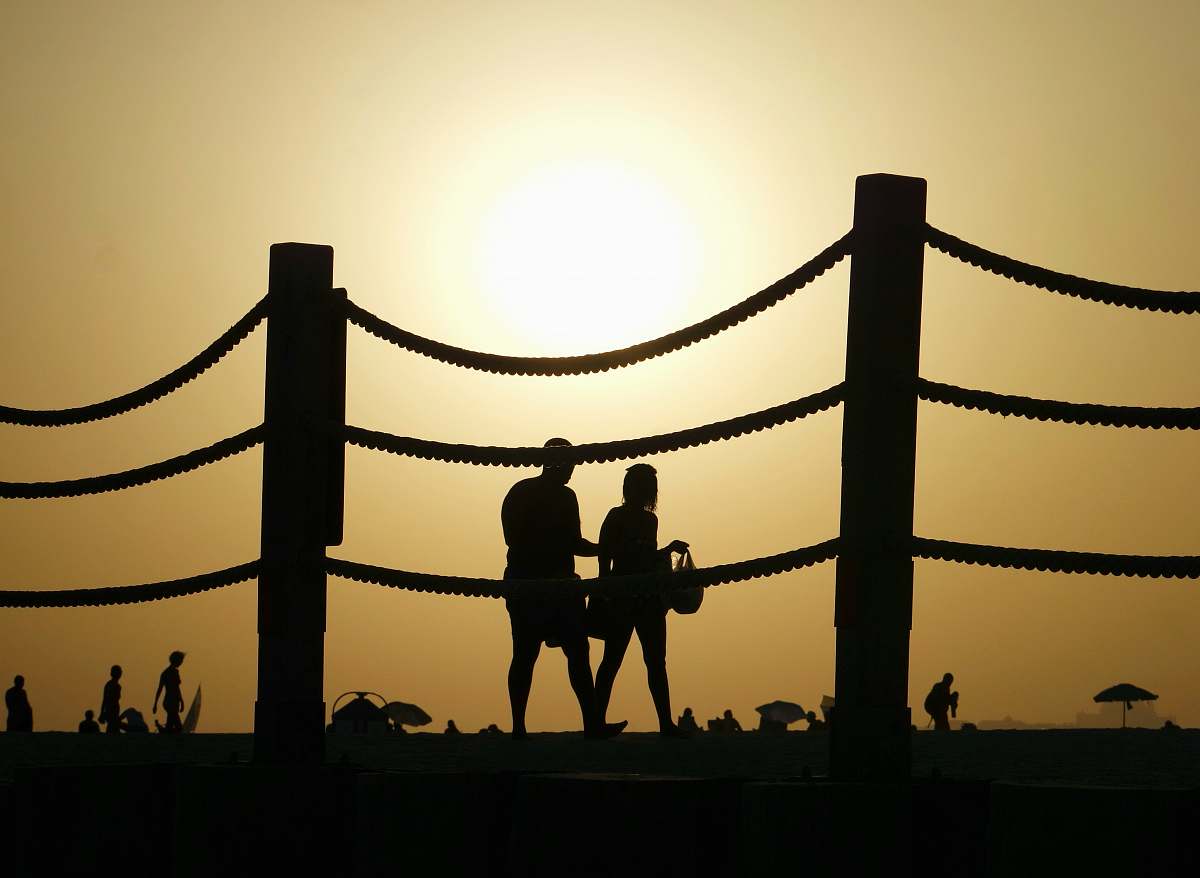 human silhouette of couple walking near fence sunlight