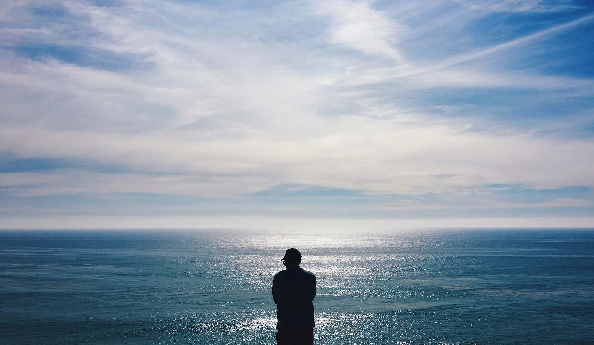 human silhouette of man facing the sea standing