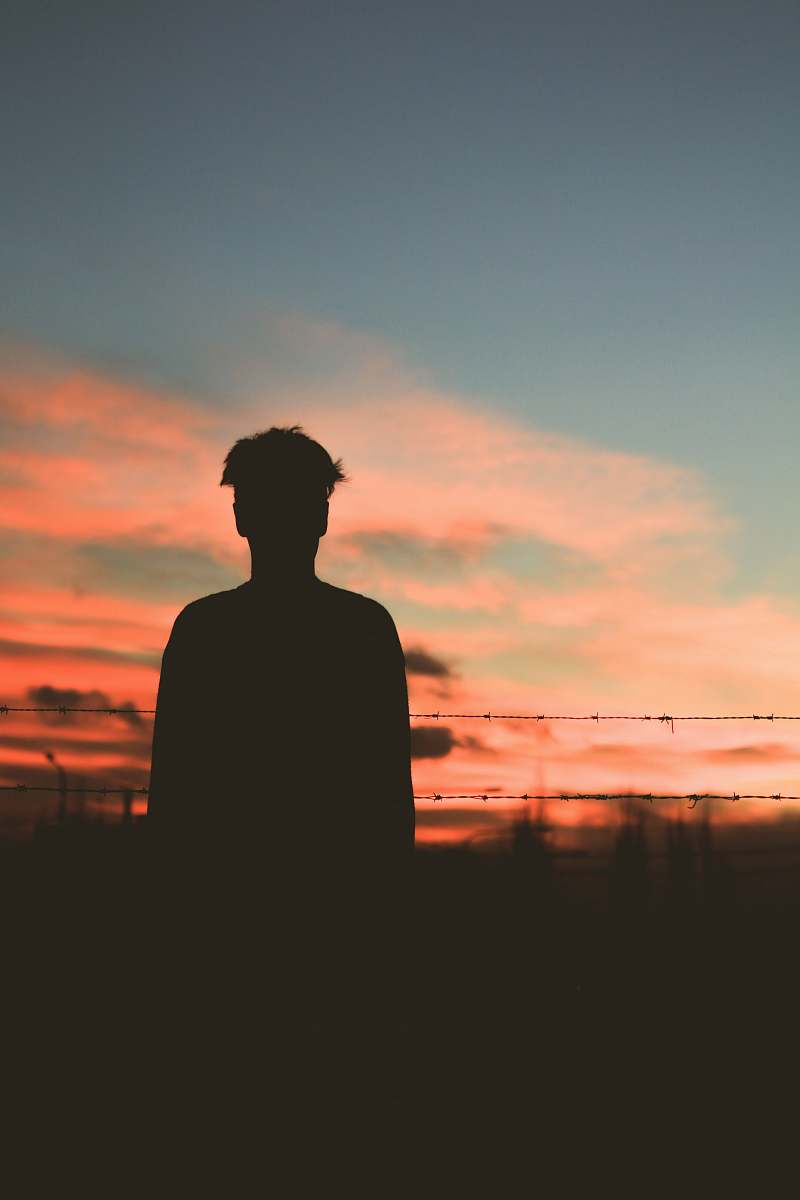 silhouette silhouette of man standing in front of fence human