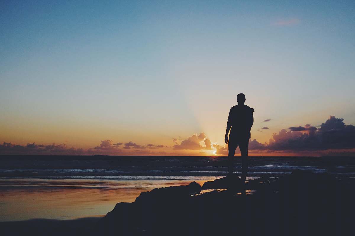 people silhouette of man standing near shoreline human