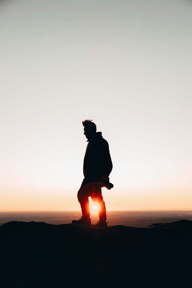 silhouette silhouette of man standing on cliff during golden hour human