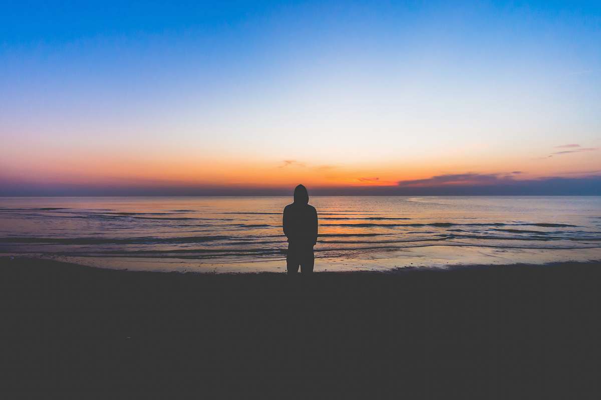 ocean silhouette of person standing near sea during golden hour sea