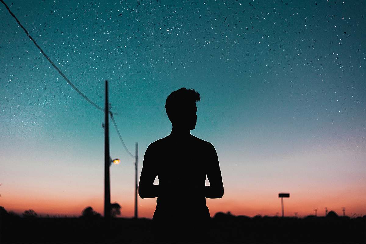 human silhouette of person standing near utility pole during night nature