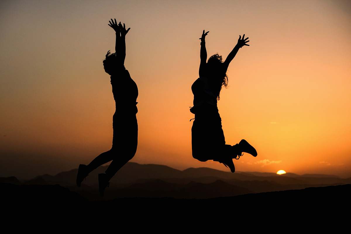 human silhouette of two jumping person during sunset silhouette