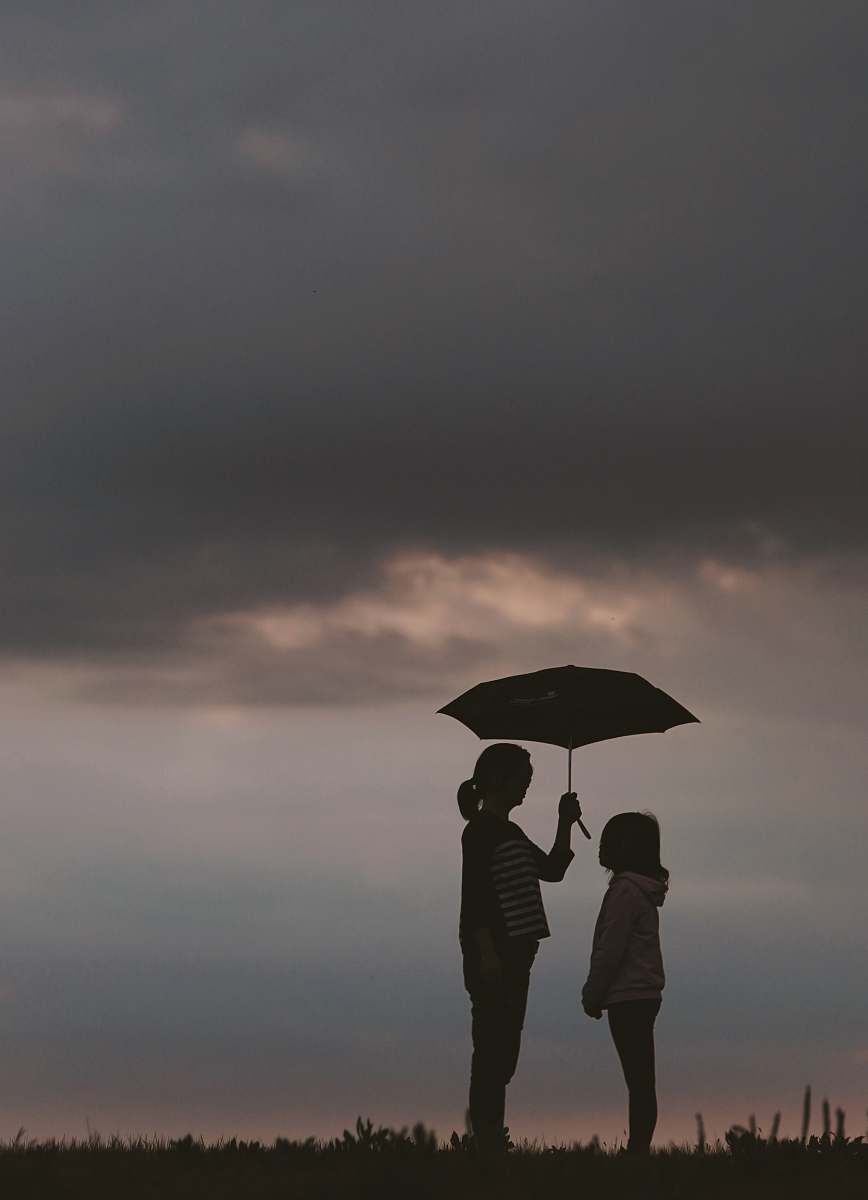 human silhouette of woman holding umbrella standing in front of girl on hill during night time people