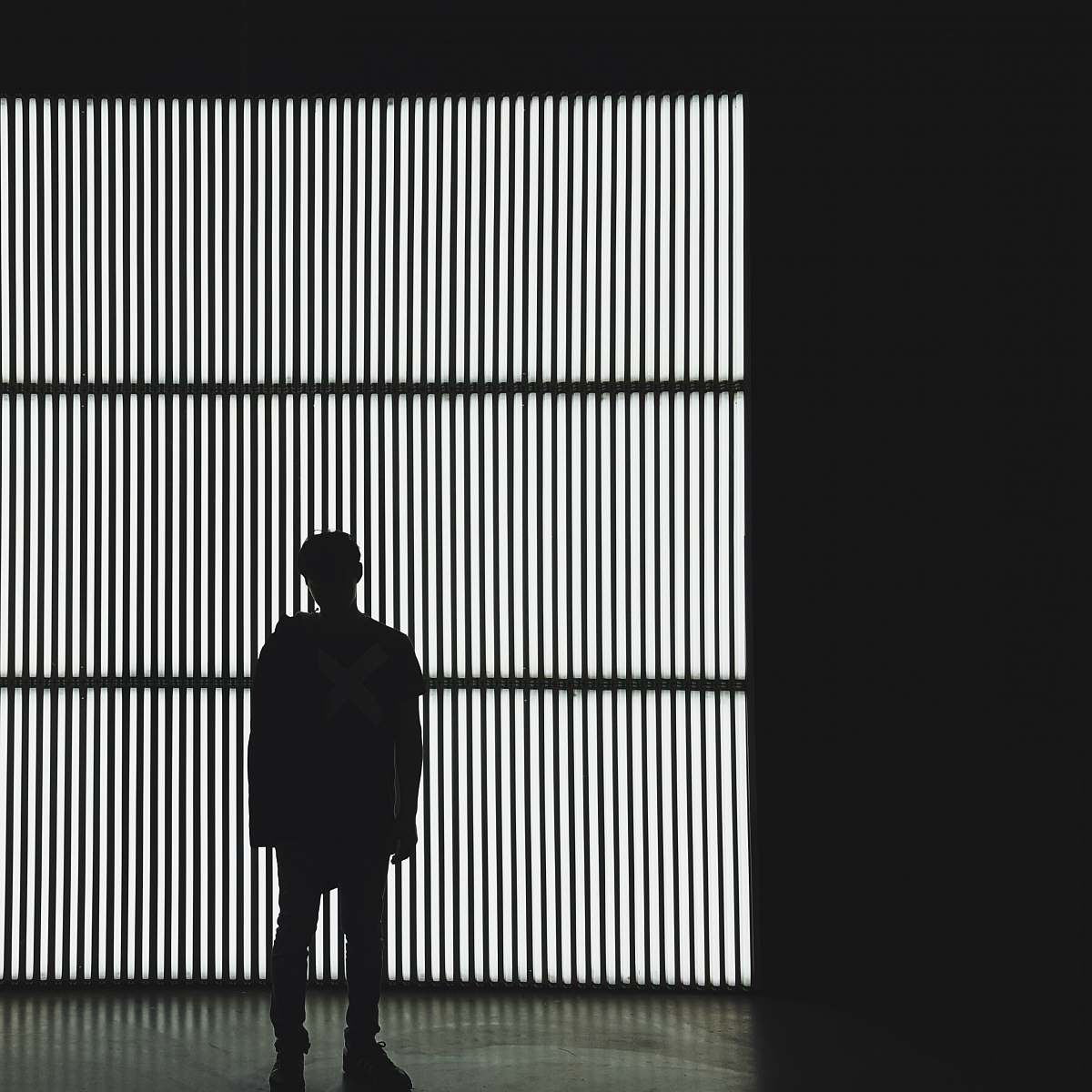 silhouette silhouette photo of a person standing near wall in dark room black-and-white