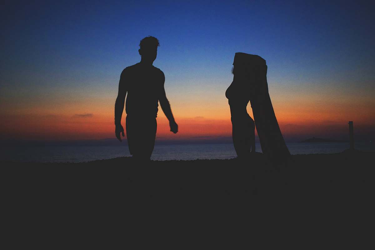 human silhouette photo of man and woman near beach people