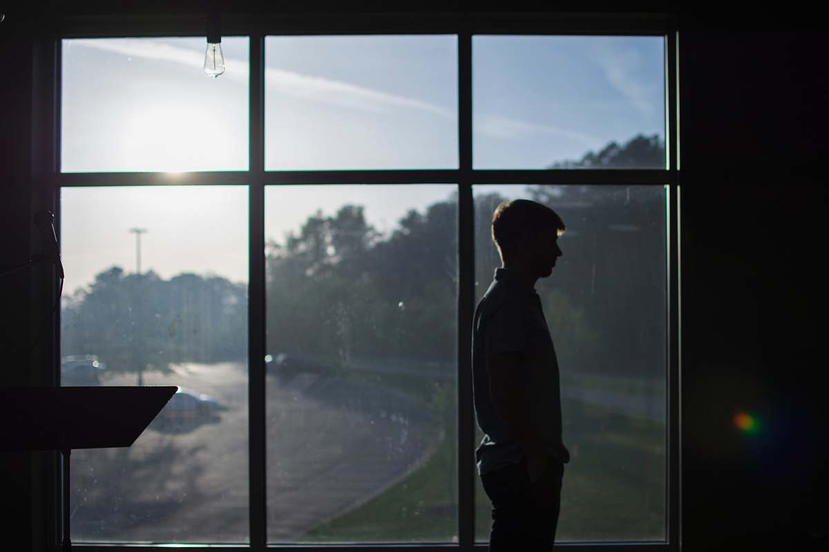 human silhouette photo of man standing near mirror window