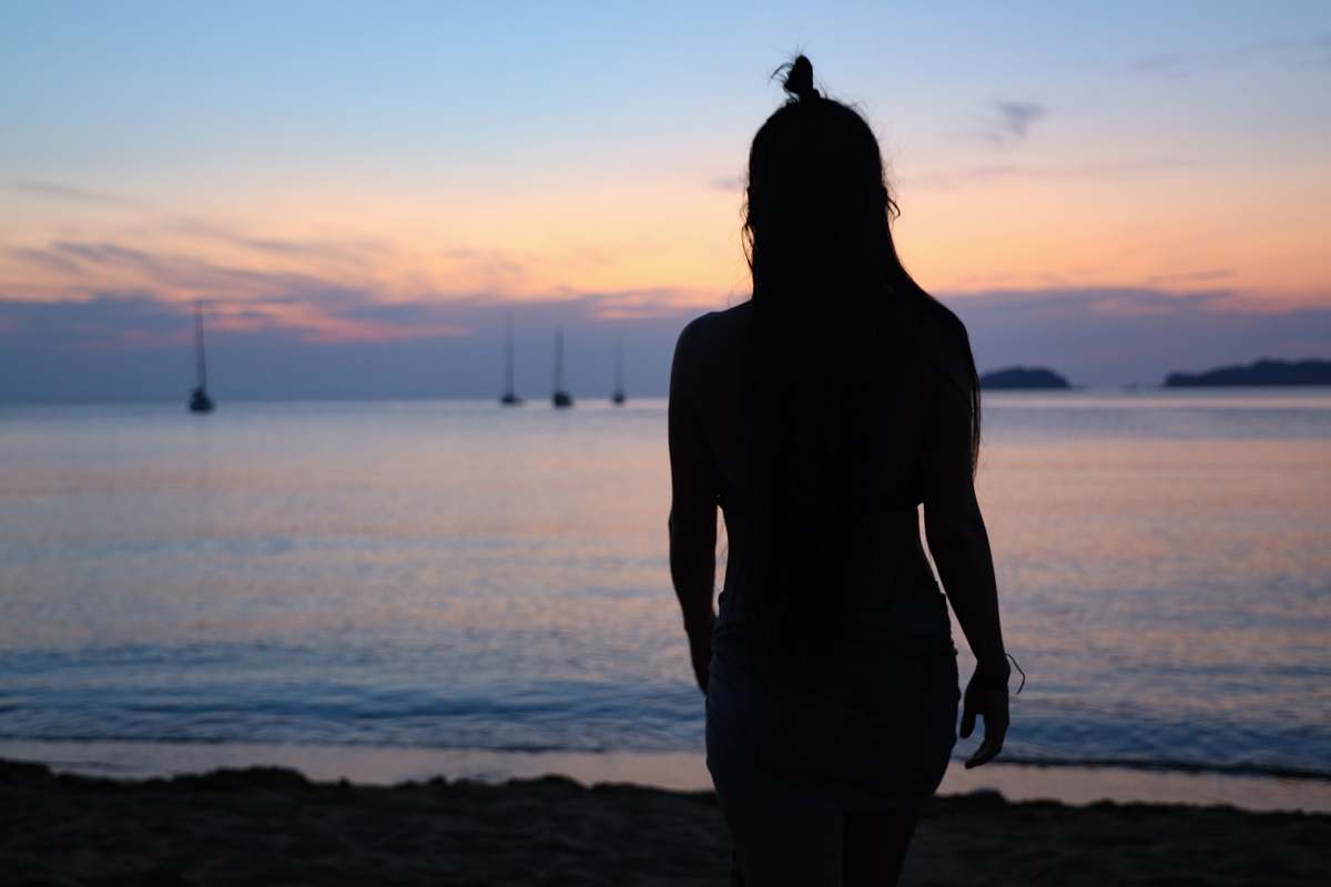 human silhouette photography of woman standing on seashore standing