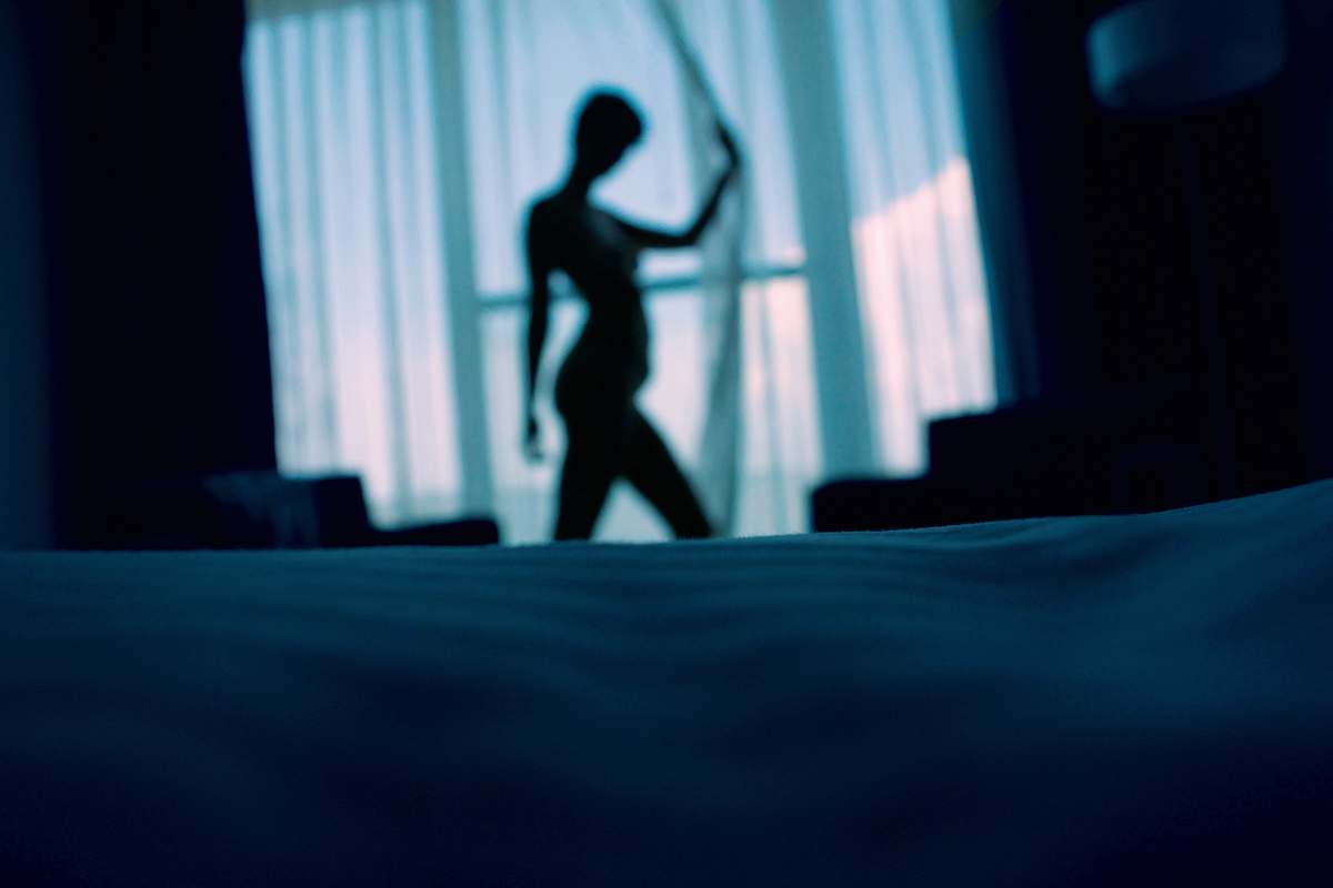 people sillouehtte photo of woman standing beside window curtains human