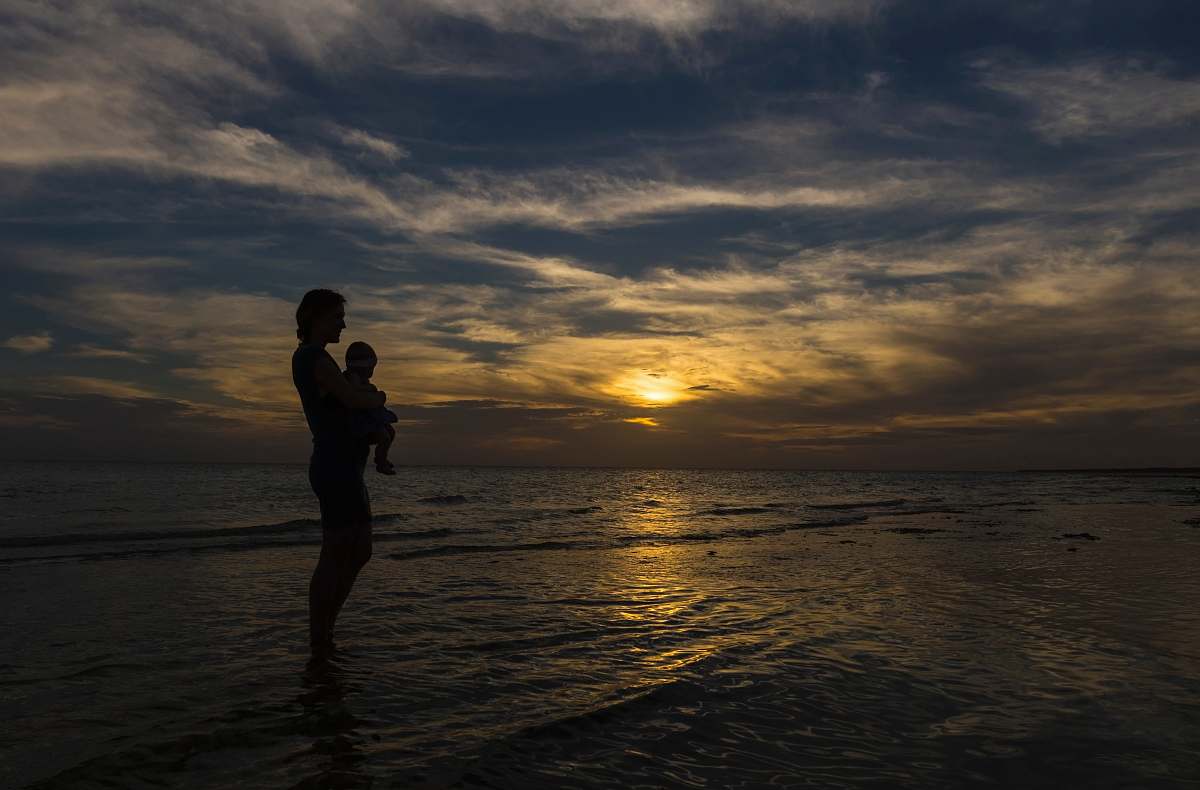 nature woman carrying baby on seashore during sunset human