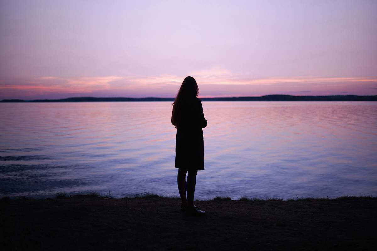 people woman standing near body of water during golden hour human