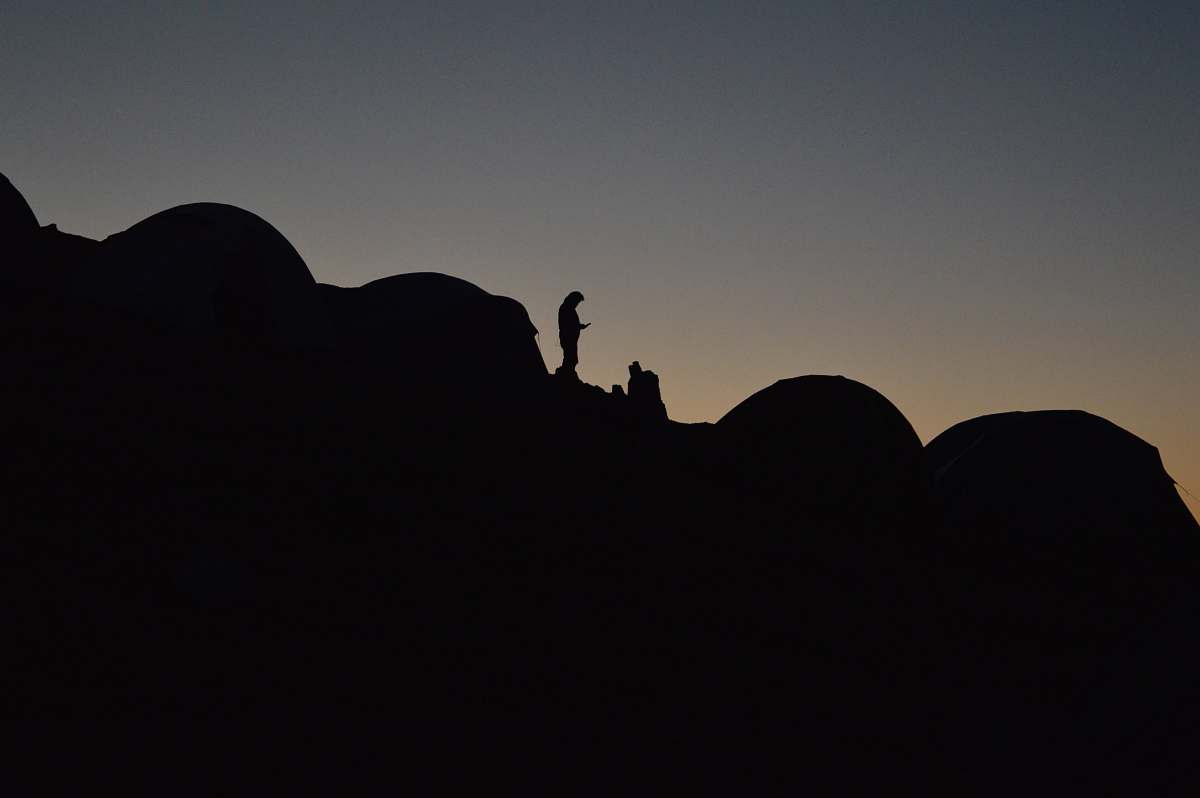 dusk A silhouette of a person in a camping site on a slope at night sunrise
