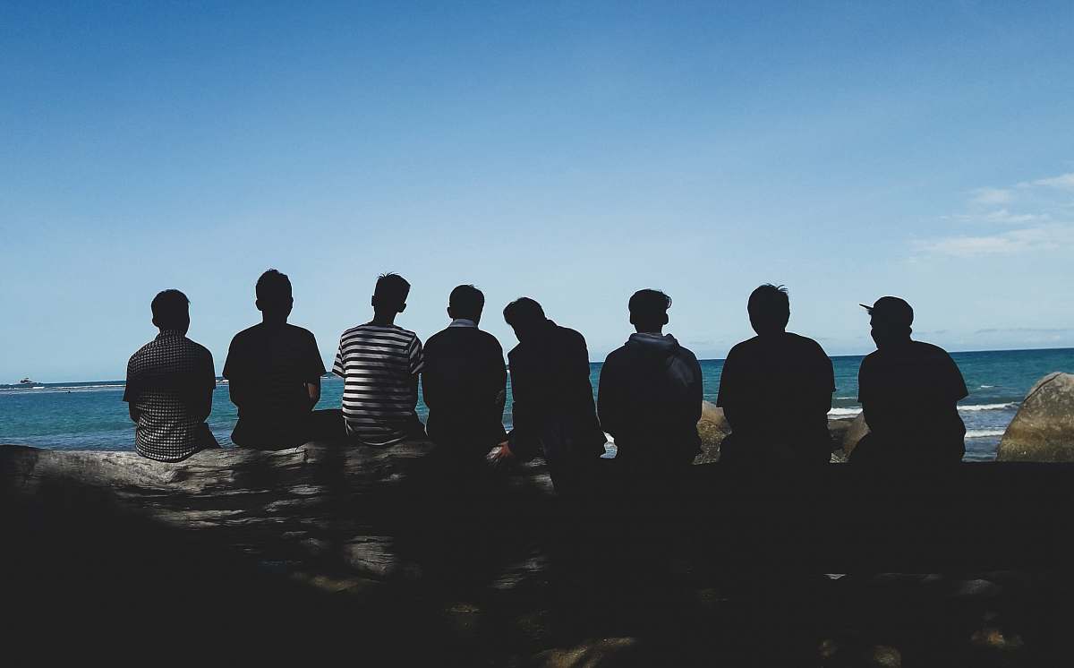 person eight man sitting on mountain cliff under blue sky human