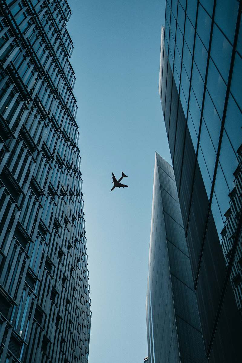 building flying airplane above high-rise airplanes office building