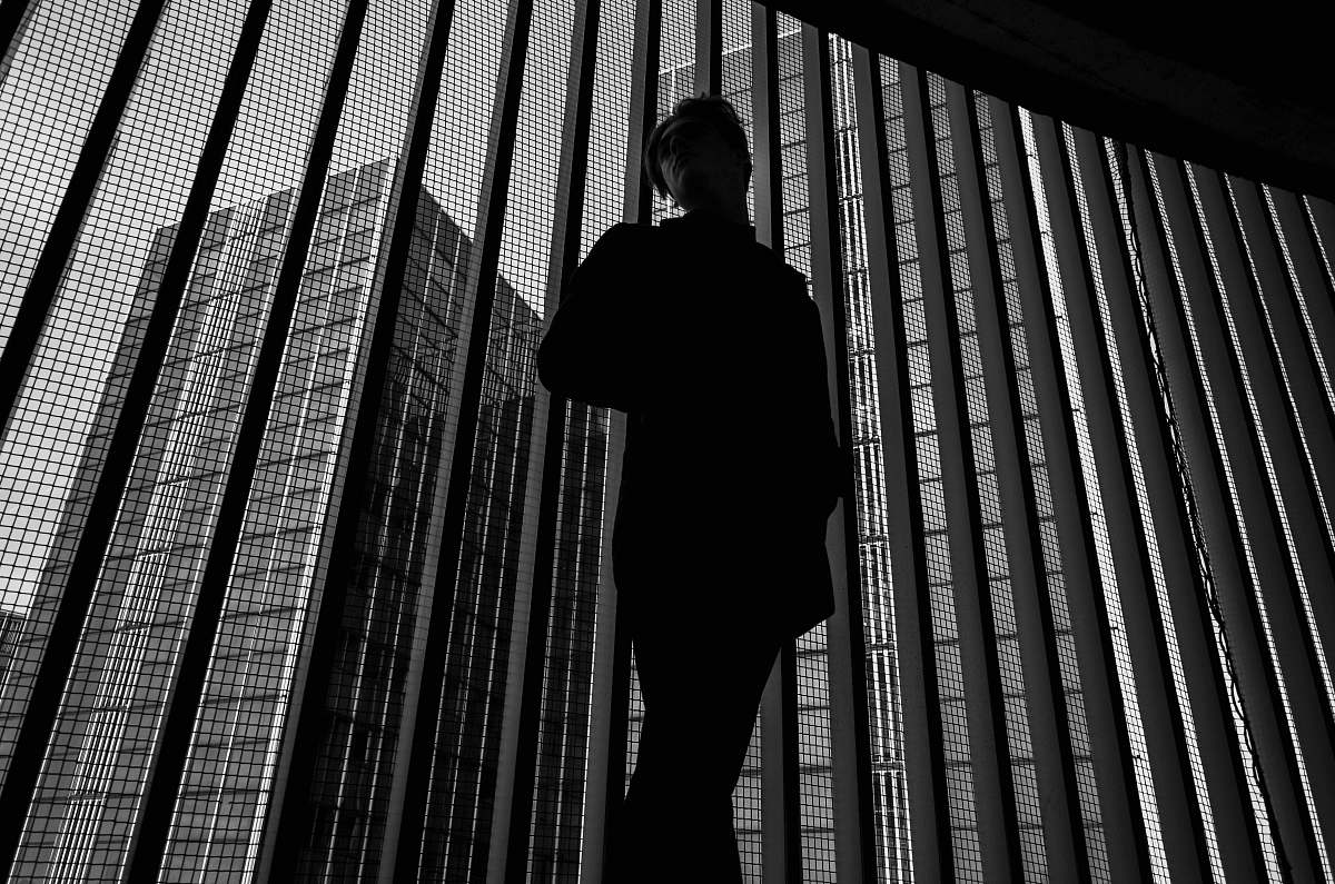 human grayscale photo of man near window black-and-white
