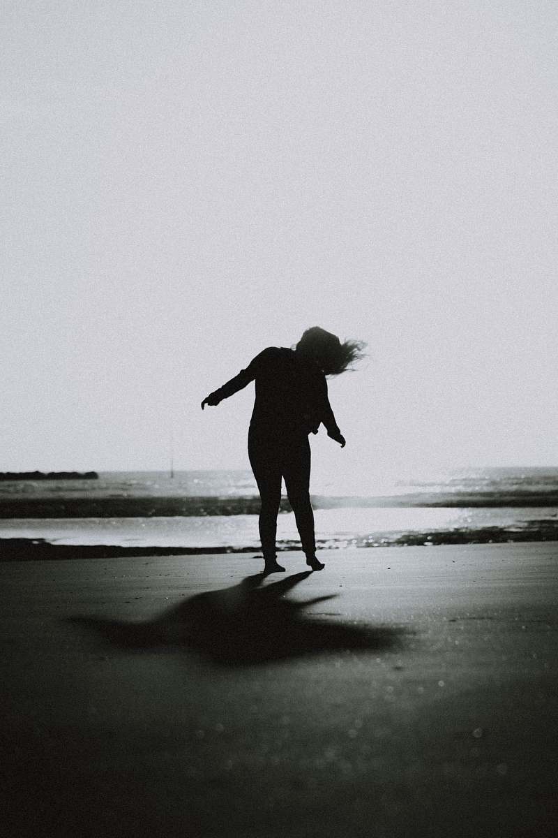 person grayscale photo of woman waving her hair on shore human