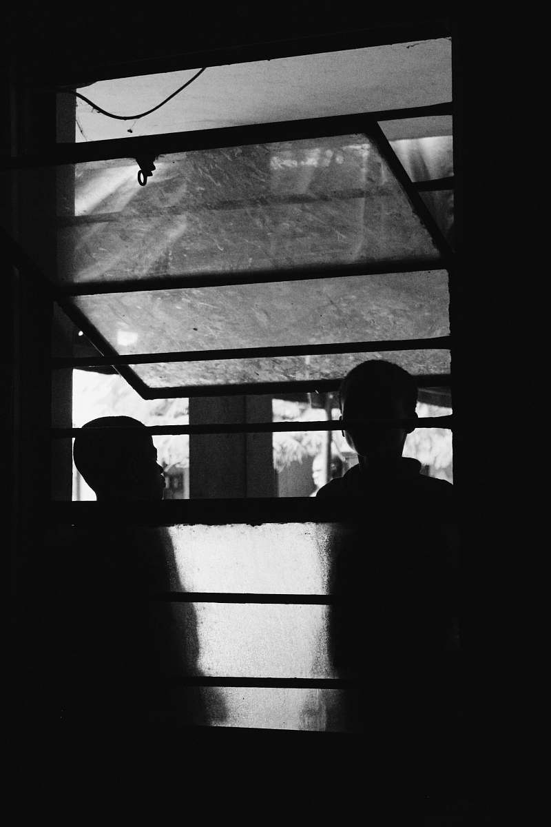human grayscale photography of two persons standing outside window black-and-white