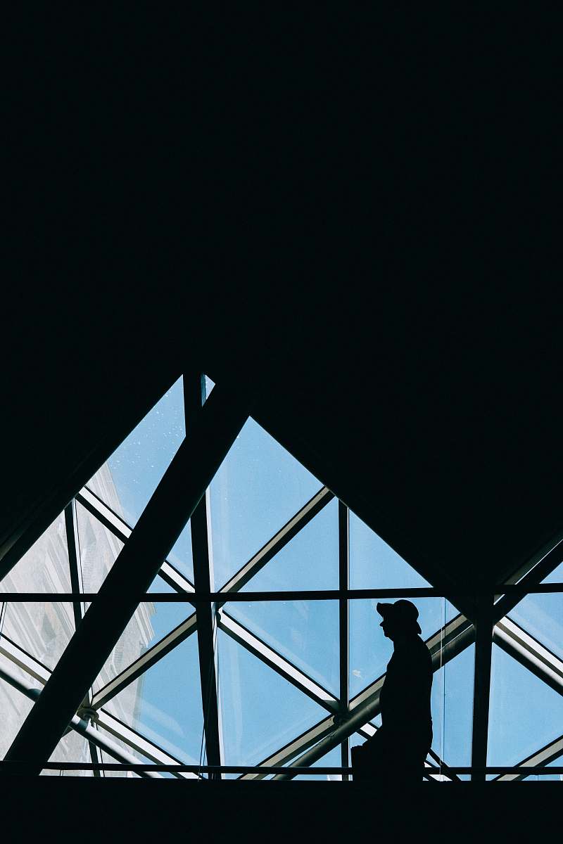 window low light photography of person walking near window skylight