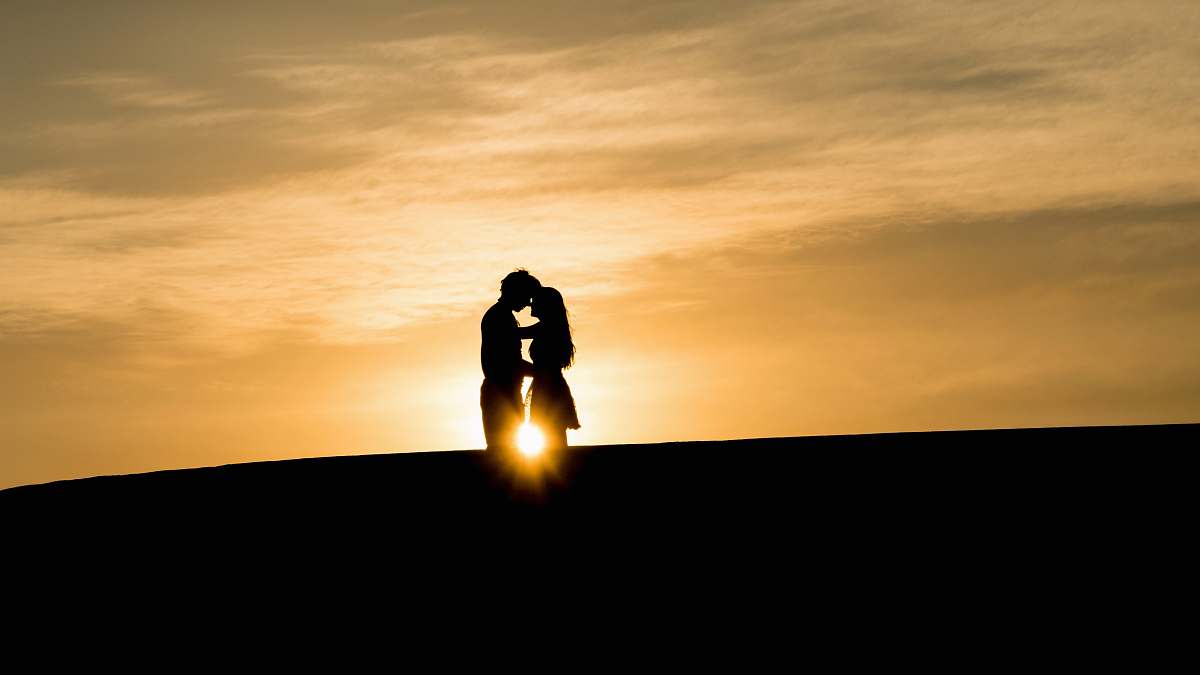 couple man and woman's silhouette on hill during golden hour man