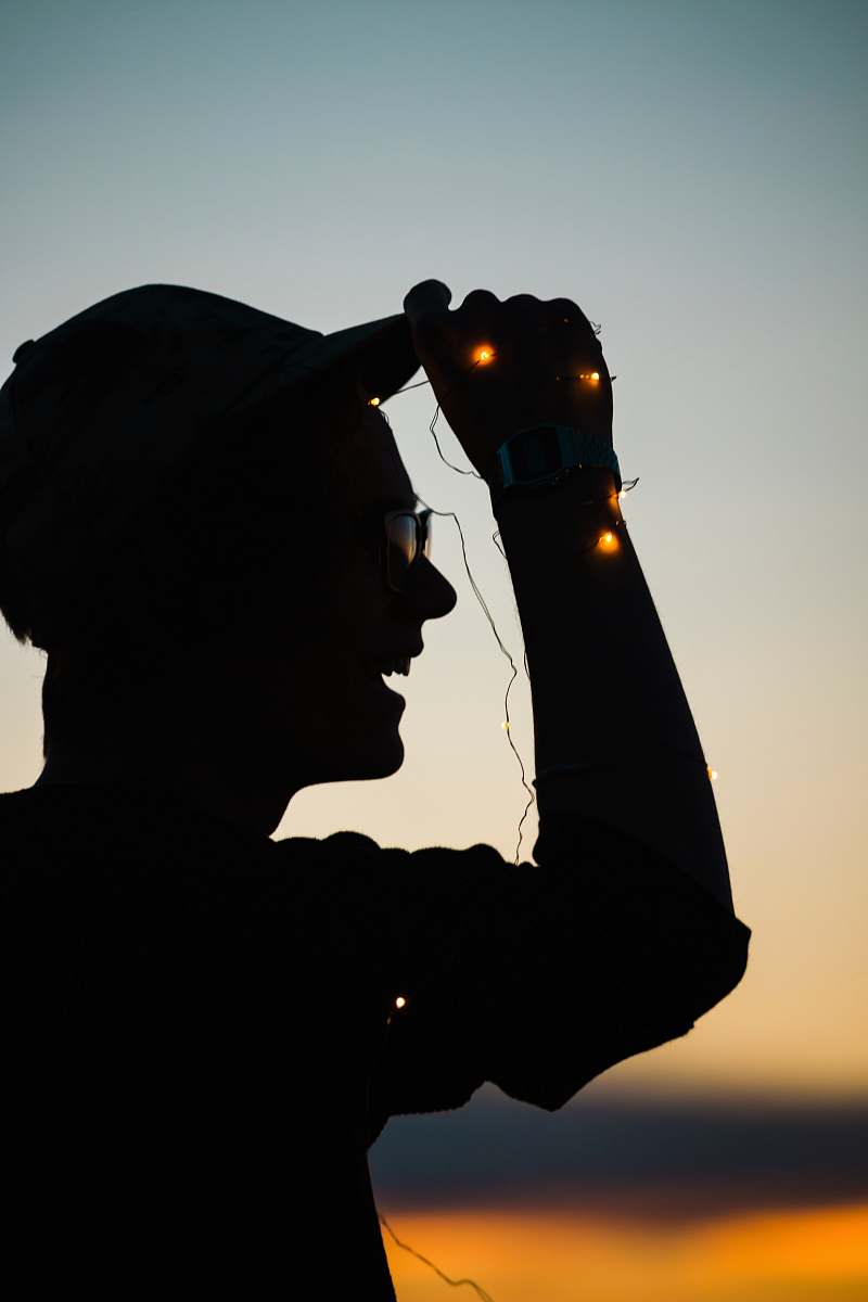 human man holding on hat while laughing silhouette person