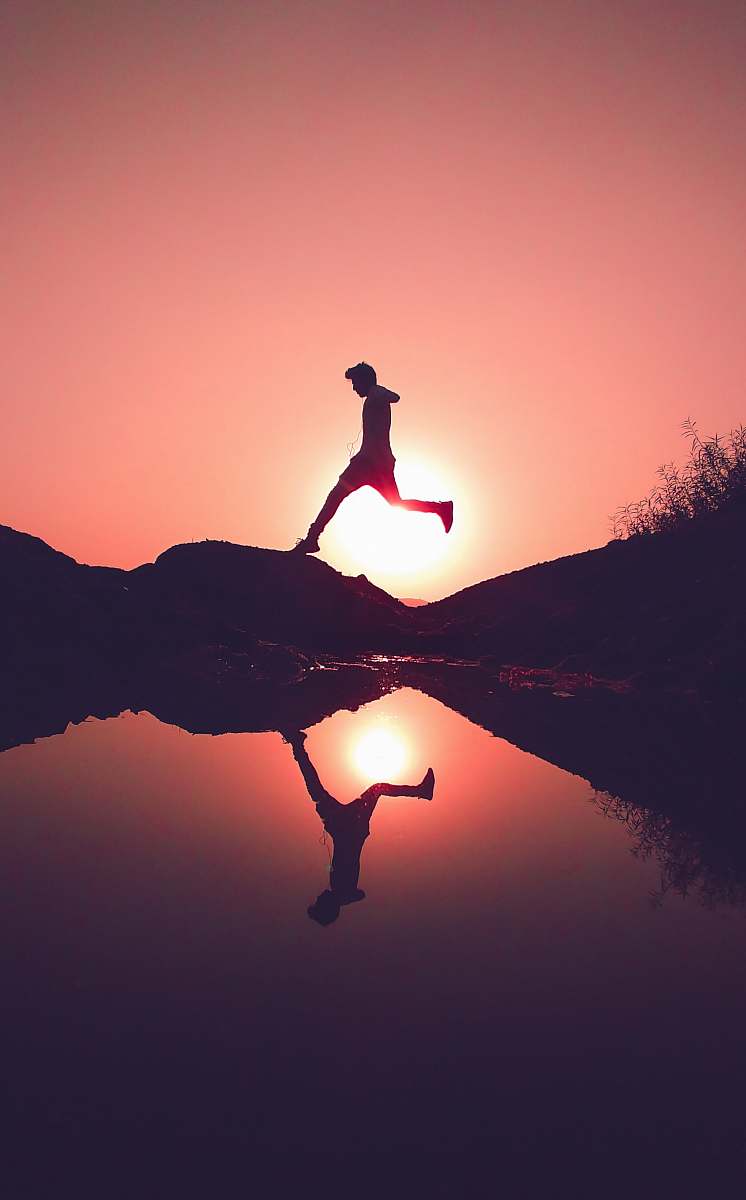 nature man jumping on rock beside lake outdoors