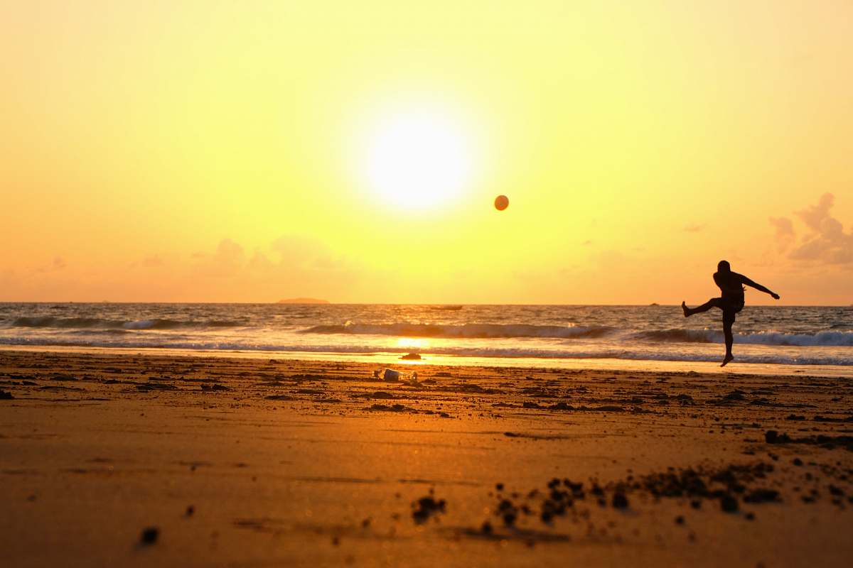 sea man kicking ball on seashore beach