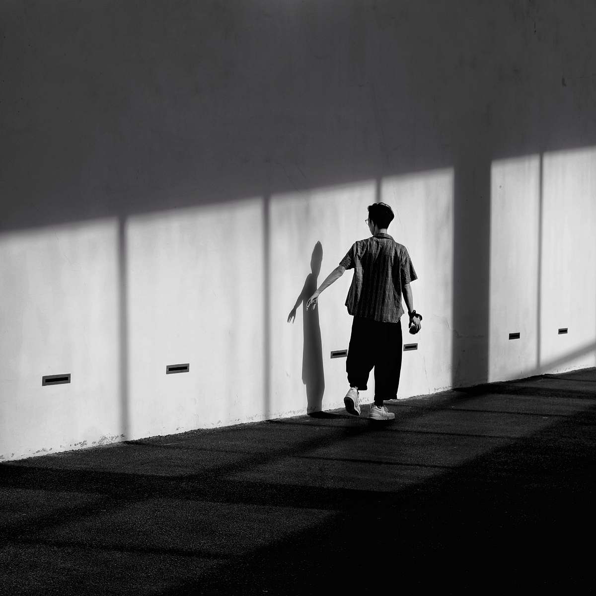 black-and-white man standing beside wall standing