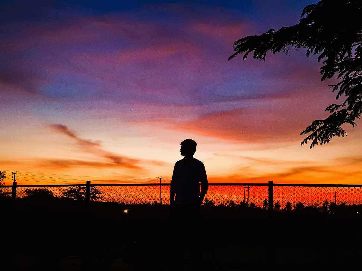 nature man standing in front of chain link fence during golden hour outdoors