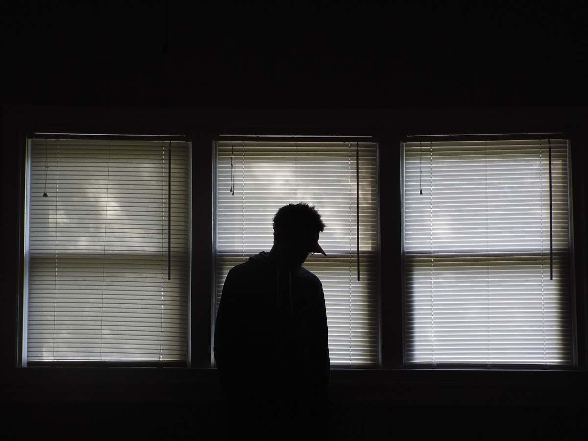 human man standing infront of window blinds person