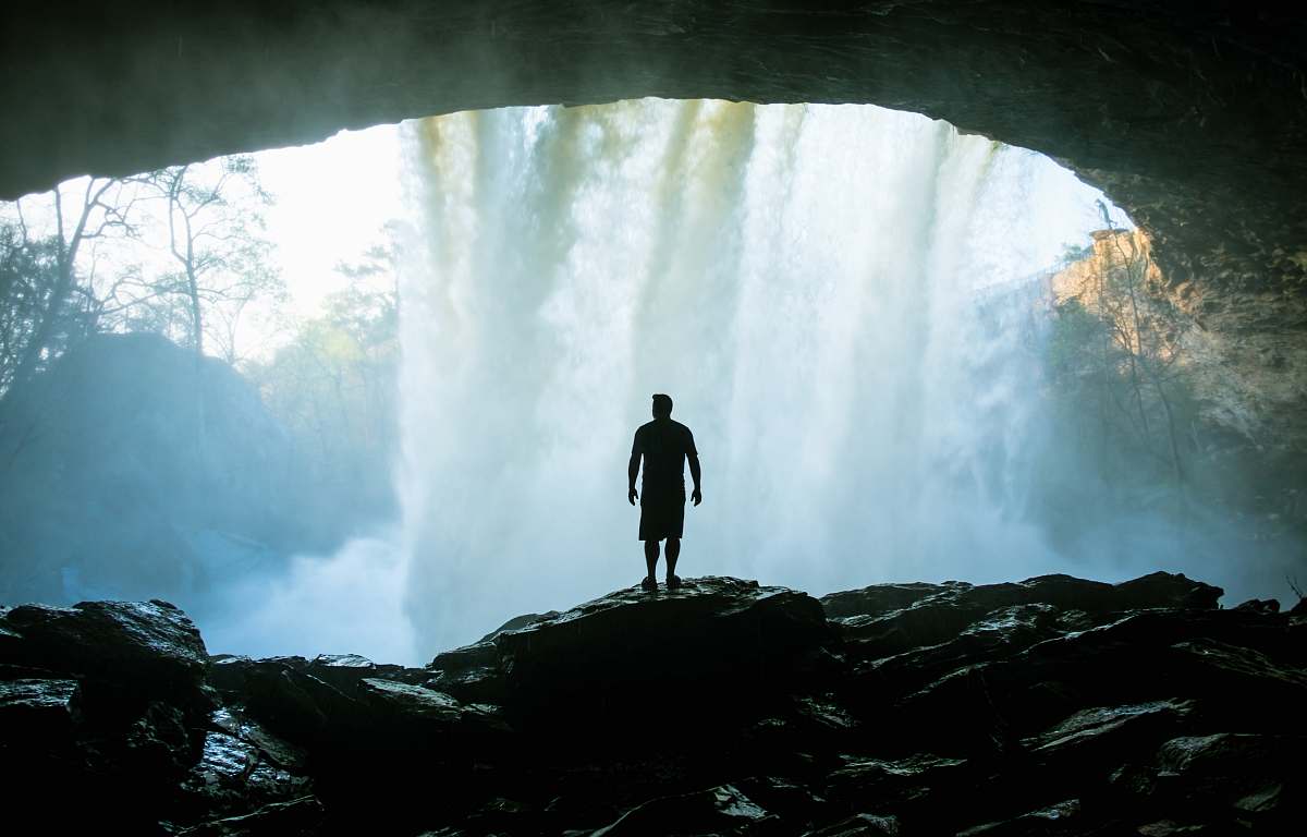 cave man standing on rock near cave rock