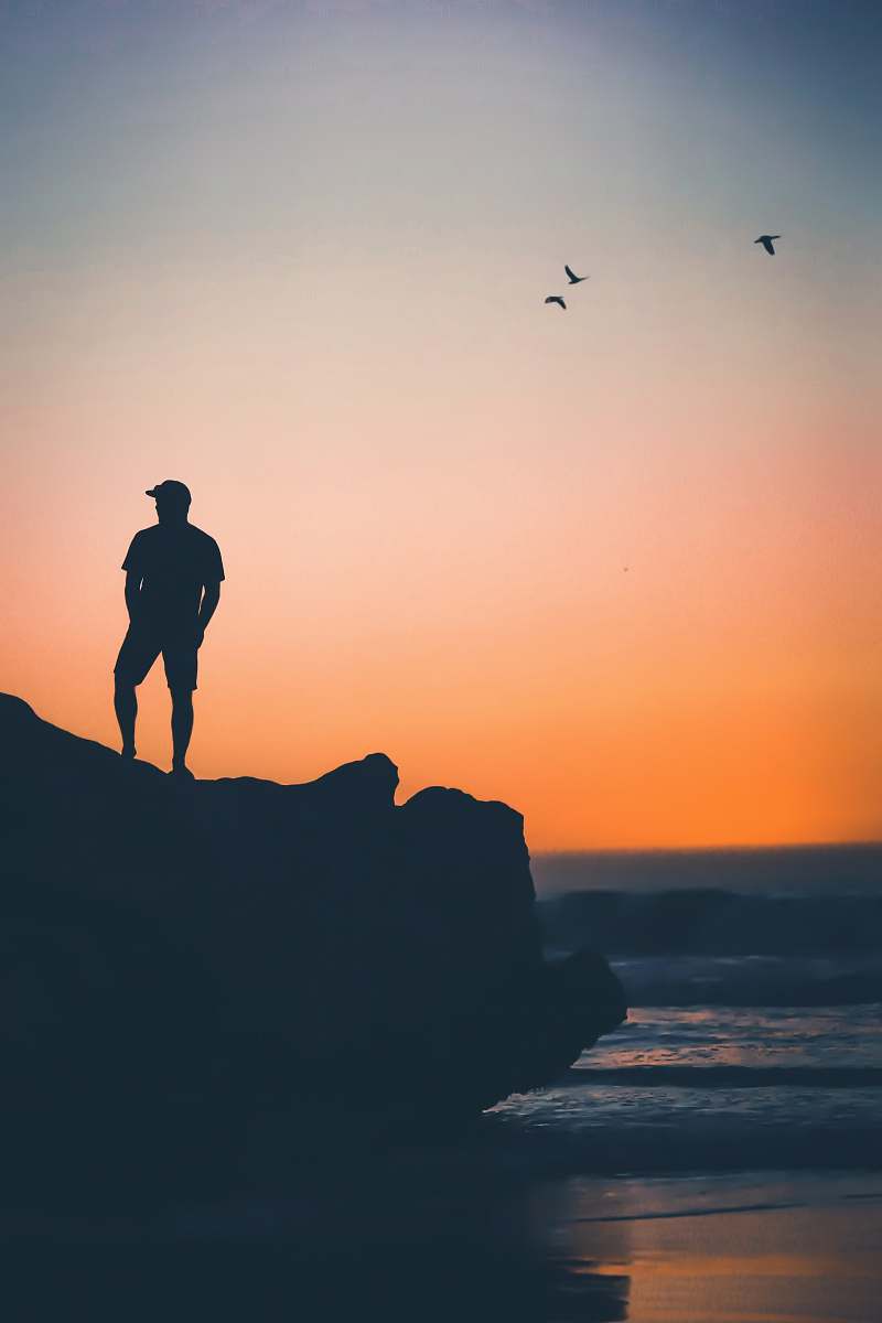person man standing on rock near on seashore people