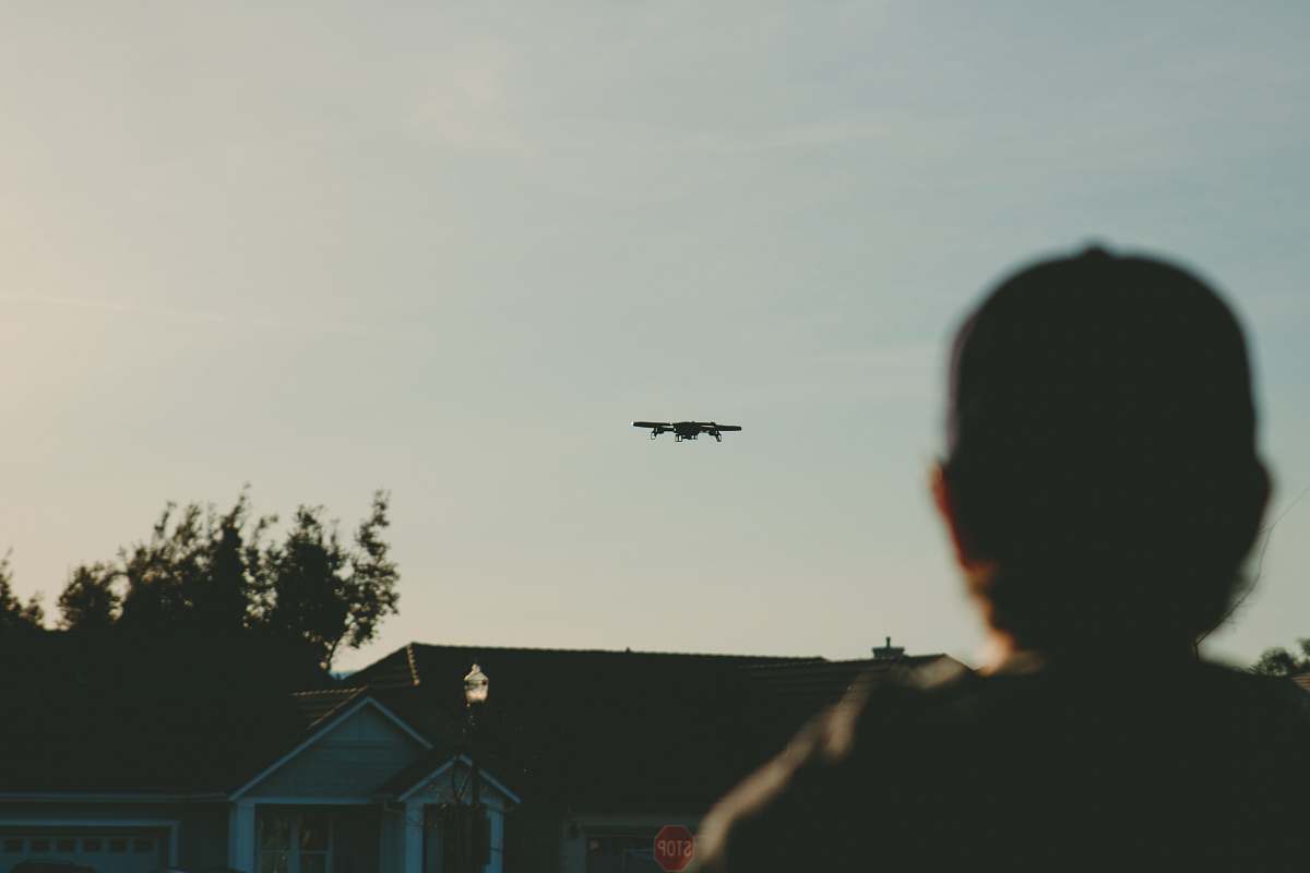 house man standing while watching plane on sky during daytime grey