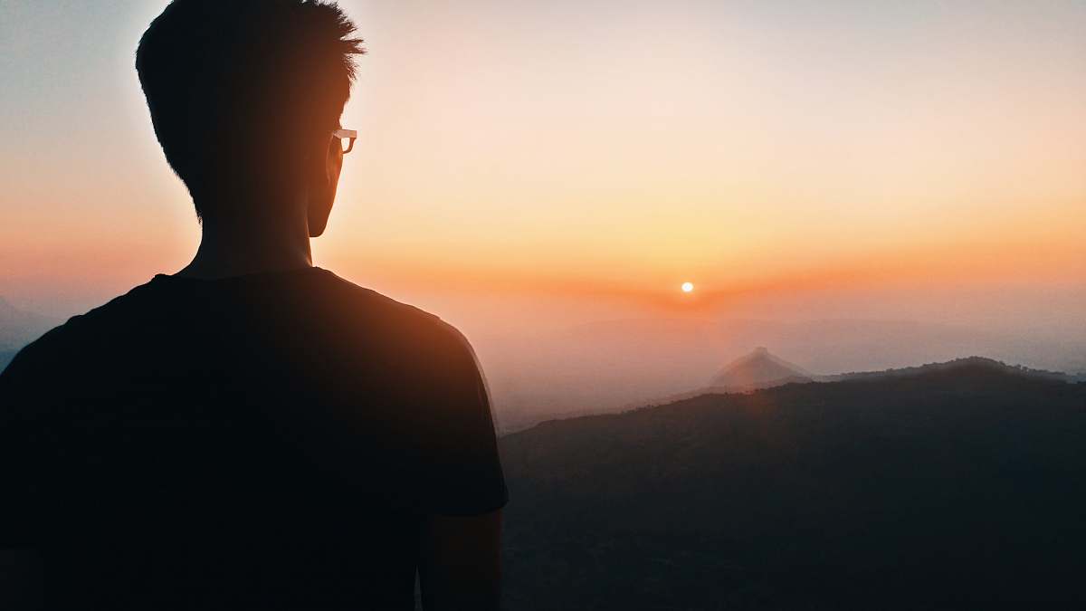 dawn man's silhouette facing mountain at golden hour dusk