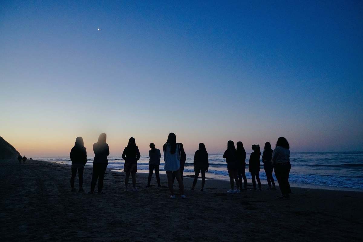 human people standing beside sea during nighttime person