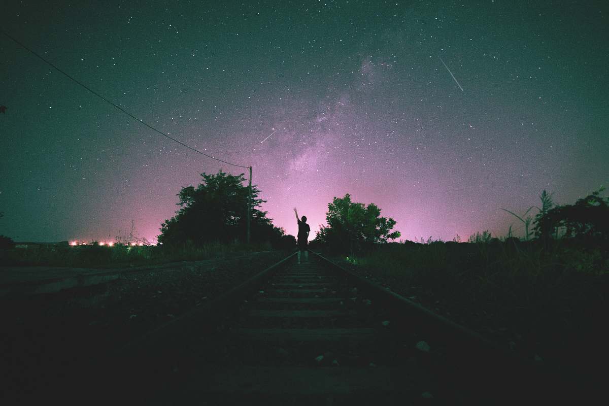 flora person in middle on train track during night time jar