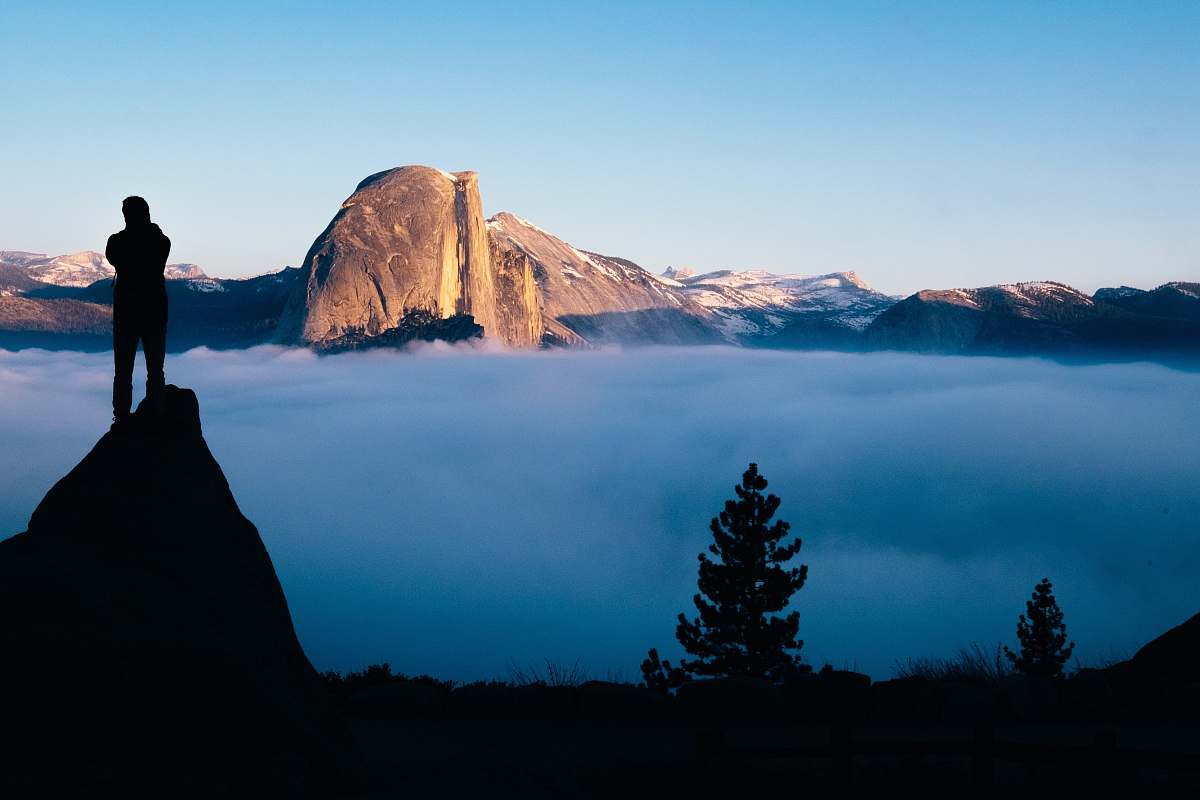 sunset person standing on cliff watching sea of clouds glacier point