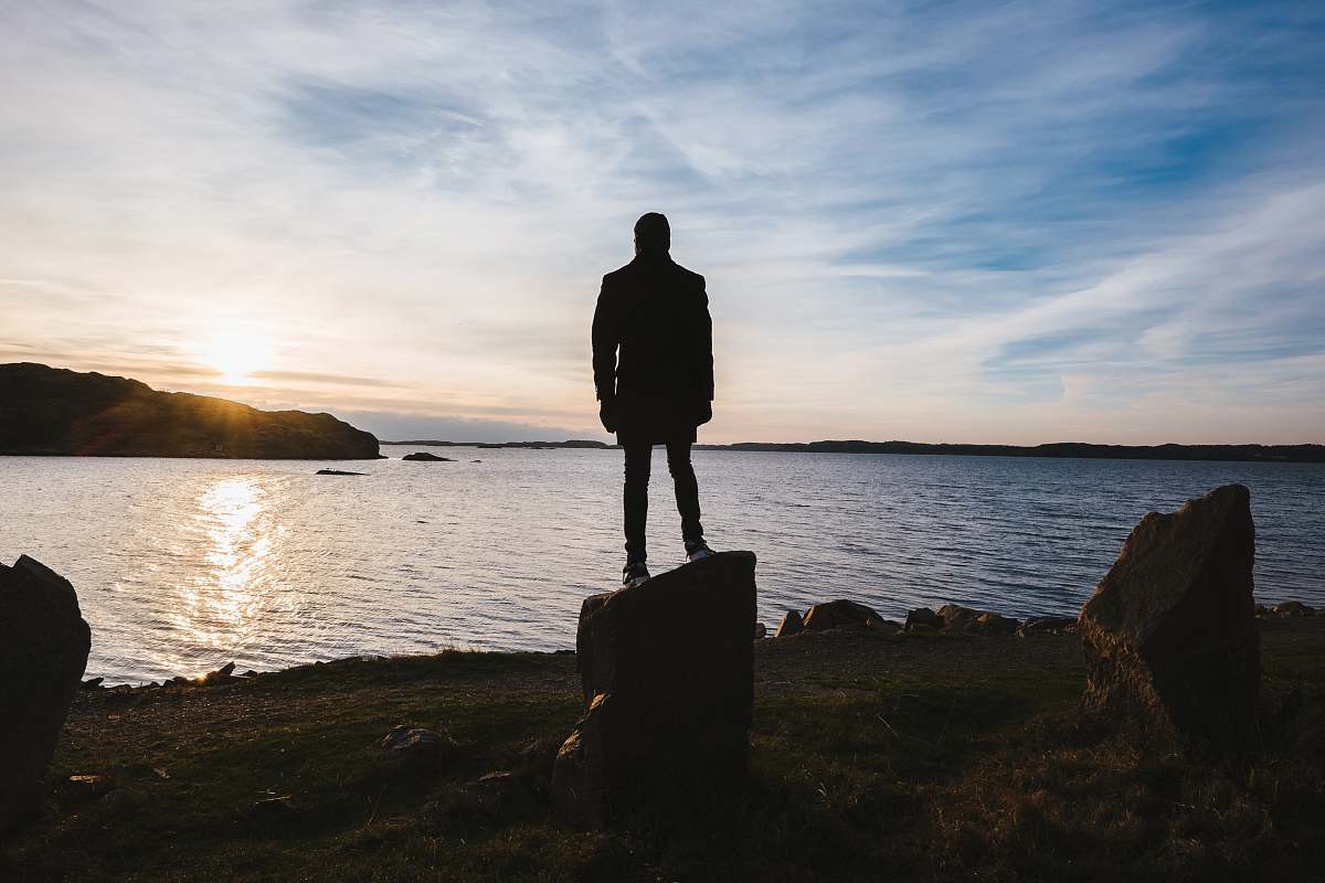 person person standing on rock facing ocean people