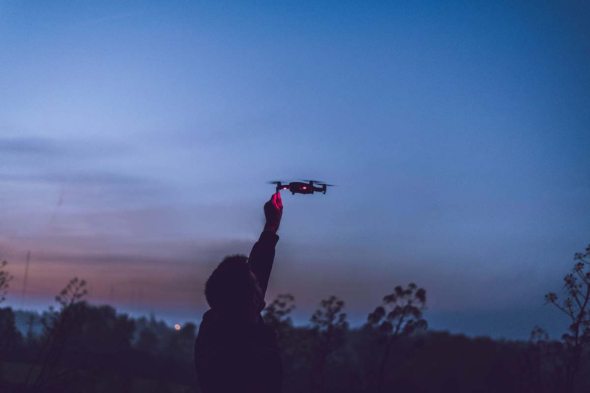 person person using black quadcopter drone during nighttime human