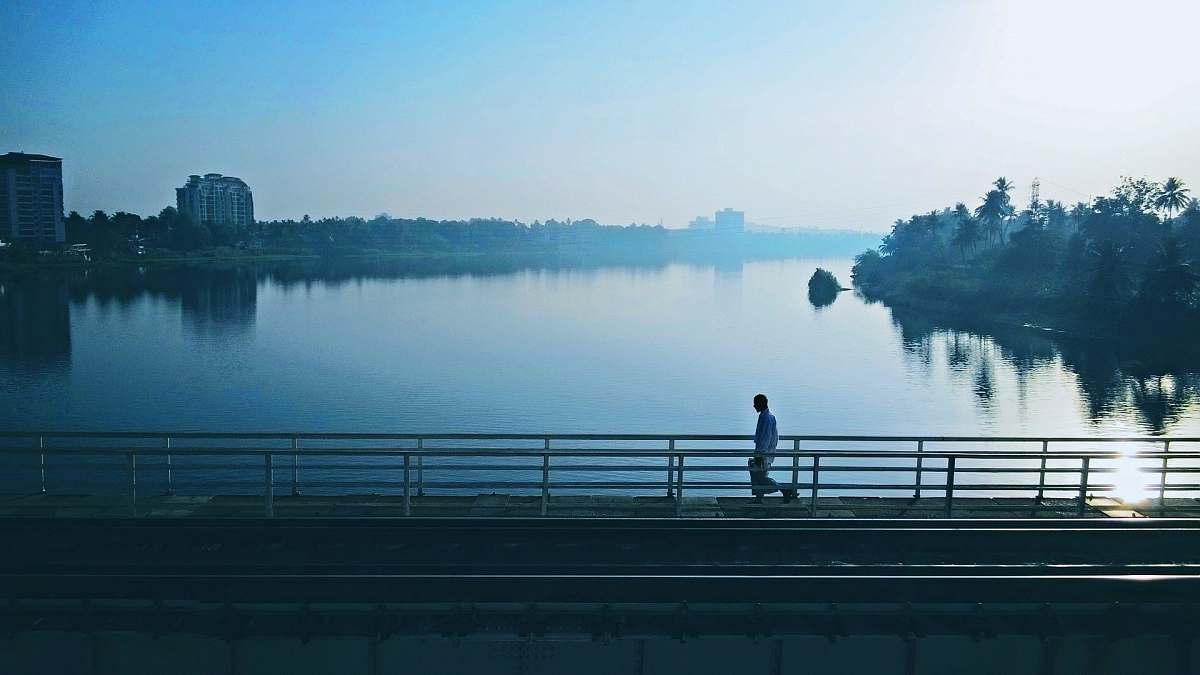 water person walking on bridge near body of water person
