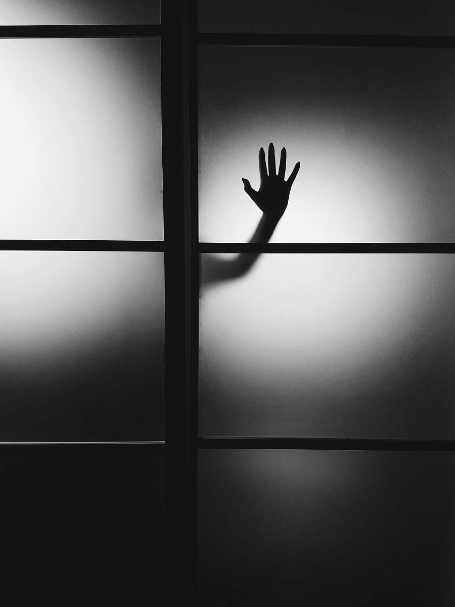 black-and-white photo of person's hand on wall hand