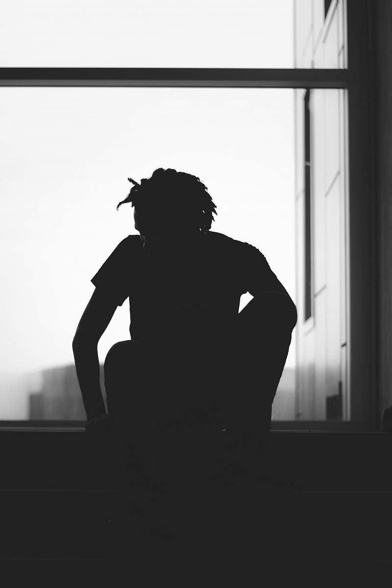 human silhouette of a person sitting near window black-and-white