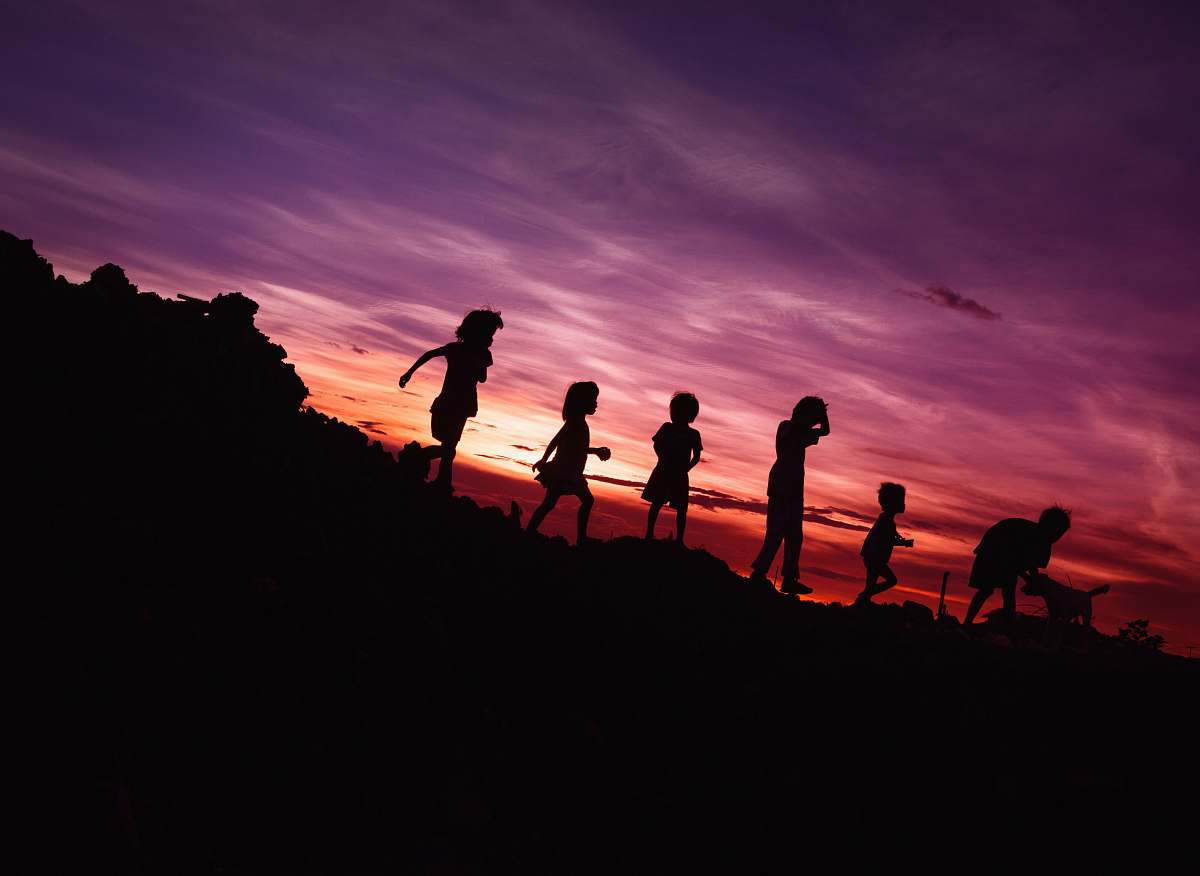sunset silhouette of children's running on hill children