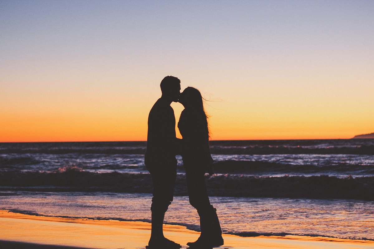 couple silhouette of couple sitting on seashore beach