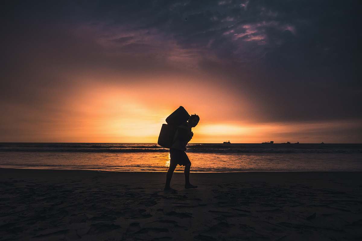 nature silhouette of man carrying container standing on shoreline outdoors
