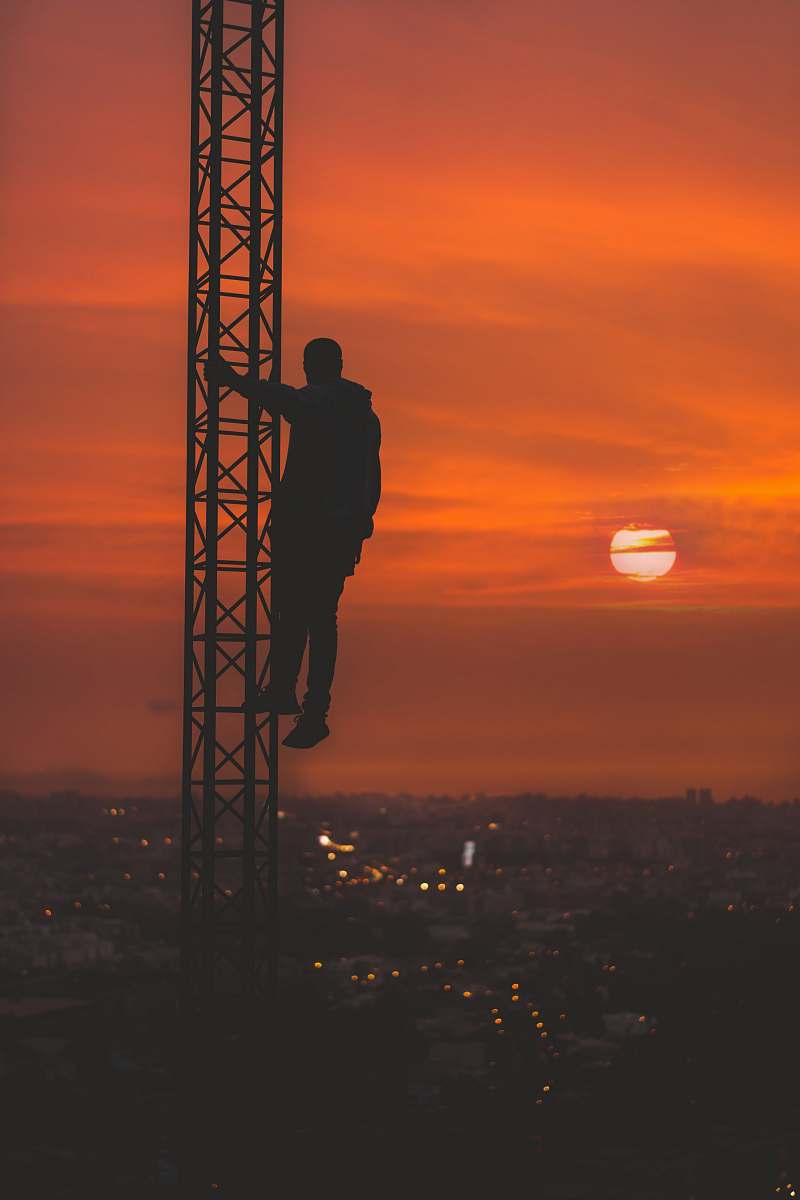 sunset silhouette of man climbing tower during sunset brown